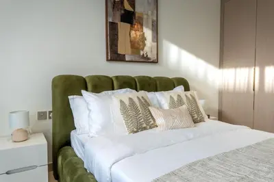 a large bed with a green headboard in a bedroom at Modern Studio JVC I Sleeps 3 I Fully Furnished in Dubai