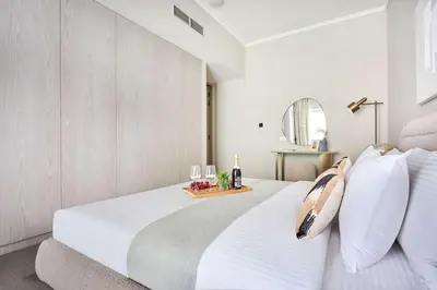 a bedroom with a white bed and a table with wine glasses at Frank Porter - Concept Residences in Dubai