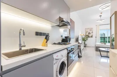 a kitchen with a sink and a washing machine at Elegant Minimal Studio with Balcony in Dubai