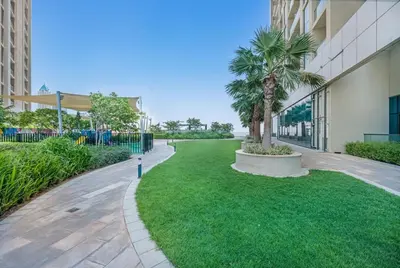 a park with palm trees next to a building at Stylish 2BR Canal Views, High Floor in Dubai
