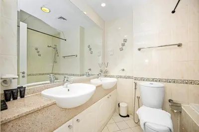 a bathroom with two sinks and a toilet and a mirror at Stunning 1BR Apartment with Breathtaking Marina Views in Dubai