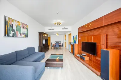 a living room with a blue couch and a tv at Stunning 1BR Apartment with Breathtaking Marina Views in Dubai