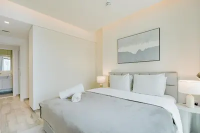 a bedroom with a large bed with white walls at RH- Premium Furnished Living in Business Bay near to Burj Khalifa in Dubai