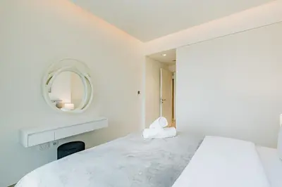 a white bedroom with a large bed and a mirror at RH- Premium Furnished Living in Business Bay near to Burj Khalifa in Dubai
