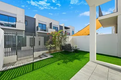 a backyard with a white fence and green grass at Golden Stays - Tranquil 4BR Villa with Pool & Coastal Charms in Dubai