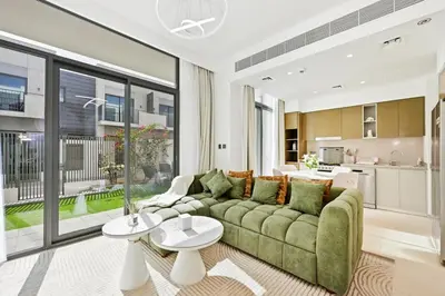 a living room with a green couch and a kitchen at Golden Stays - Tranquil 4BR Villa with Pool & Coastal Charms in Dubai