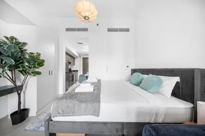 a bedroom with a large bed with blue pillows at Stylish Bella Rose Stay Pool & Gym in Dubai