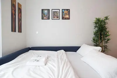 a white bed in a room with pictures on the wall at Luxury 1BR Lake View Near Metro & Marina in Dubai