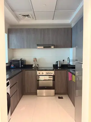 a kitchen with wooden cabinets and a stove top oven at Orchid residence 1BHK apartment in Dubai