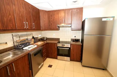 a kitchen with wooden cabinets and a stainless steel refrigerator at Signature Luxury 2Bedroom Burj Khalifa Fountain View in Dubai