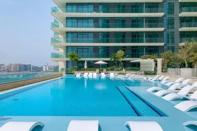 a swimming pool with lounge chairs and a building at Panoramic Sea View, Offering Direct Access to Beach, Three Bedrooms and Assistant Room - Beach Vista Tower 2 by Deluxe Holiday Homes in Dubai