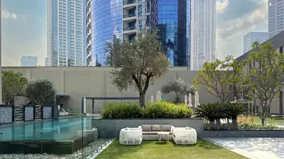a hotel with a pool and chairs and buildings at Stylish 1 BR with hotel facilities and canal view in Dubai