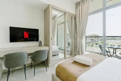 a bedroom with a bed and a tv and a table at RH-Smart Studio Near Expocity & Al Maktoum Airport in Dubai