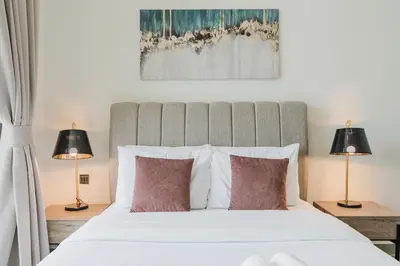 a bedroom with a large white bed with two lamps at RH-Smart Studio Near Expocity & Al Maktoum Airport in Dubai