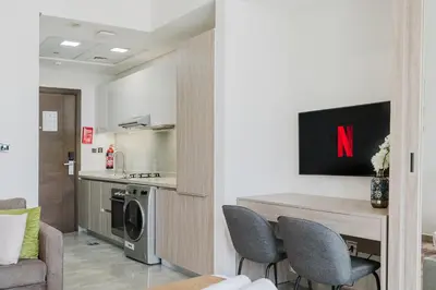 a living room with a table and chairs and a kitchen at RH-Smart Studio Near Expocity & Al Maktoum Airport in Dubai