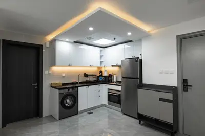 a kitchen with white cabinets and a black refrigerator at Dubai Marina - 1 BHK Elegant & Modern Apartment in Dubai