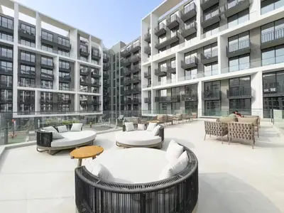 a large building with tables and couches in a courtyard at Stylish modern studio near Miracle Garden with Gym, Pool and Padel court in Dubai