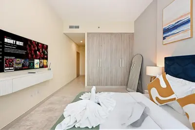 a white bedroom with a bed and a tv at Golden Stays - Opulent 2BR View Residence at The Bay in Dubai