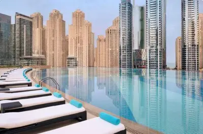 a pool with chaise lounges in front of a city at Highest 1BR in JW Marriott Marina with Marina Views in Dubai