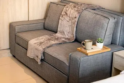 a grey couch with a coffee mug on a wooden tray at Seven Palm! Rooftop Infinity Pool with Great View! Private Beach Access! in Dubai
