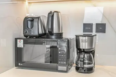 a microwave and a coffee maker on a counter at Golden Stays - Chic 1BR Oasis Serene & Private in Dubai