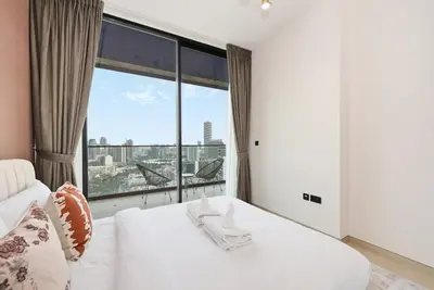 a bedroom with a white bed and a large window at Golden Stays - Chic 1BR Oasis Serene & Private in Dubai