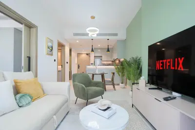 a living room with a white couch and a television at KeyRock Living - Luxury Apartment with Pool & Gym in Dubai