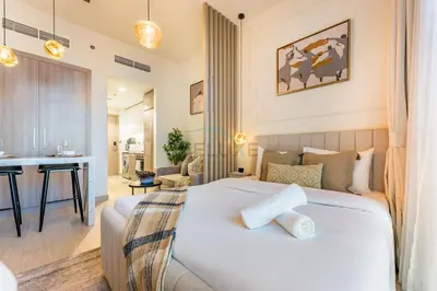 a bedroom with a white bed and a living room at Contemporary Studio Apartment with Balcony & Community Views - Azizi Riviera 48, Al Merkadh by Deluxe Holiday Homes in Dubai