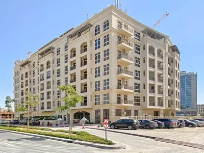 a large building with cars parked in a parking lot at Prestige Urban Escape 2BDR In La Fontana in Dubai