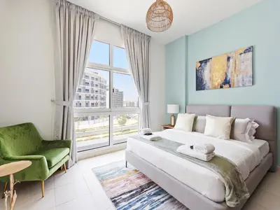 a bedroom with a large bed and a green chair at Prestige Urban Escape 2BDR In La Fontana in Dubai