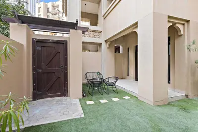a patio with two chairs and a wooden door at Silkhaus Private Garden in Old Town Zanzebeel Bldg in Dubai