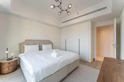 a white bedroom with a large bed and a chandelier at HAVN - 1 bedroom in Madinat Jumeirah Living in Dubai
