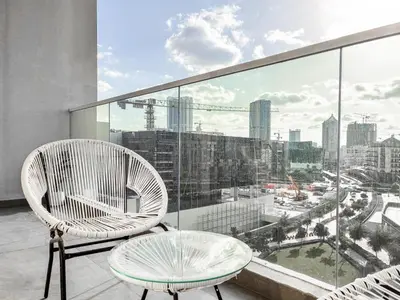 a balcony with two chairs and a table and a view of a city at Jewelz by Danube, Arjan, Al Barsha - Onelink in Dubai