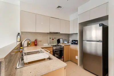 a kitchen with white cabinets and a stainless steel refrigerator at Rentico l Ultra Luxury 2BR Burj Khalifa & Fountain in Dubai