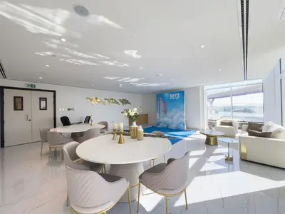 a room with tables and chairs and a couch at Luxury 1BR - Miracle Garden View - Skyz in Arjan in Dubai
