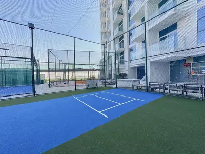 a tennis court in front of a building at Luxury 1BR - Miracle Garden View - Skyz in Arjan in Dubai