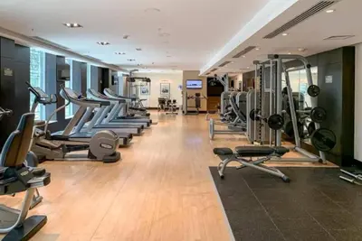a gym with a row of treadms and machines at FIRST CLASS 1BR Elegance Near Burj Khalifa in Dubai