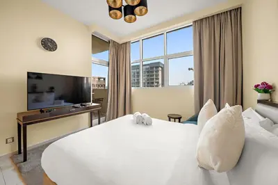 a bedroom with a white bed and a large window at FIRST CLASS Studio Cozy Luxe Retreat in Dubai