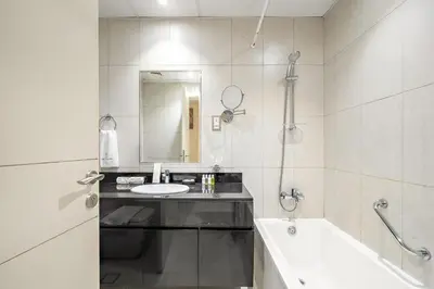 a white bathroom with a sink and a bath tub at FIRST CLASS Studio Cozy Luxe Retreat in Dubai