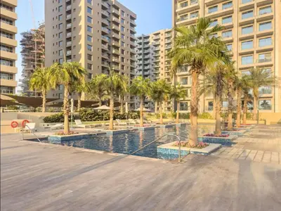 a swimming pool with palm trees and buildings at FIRST CLASS Studio Cozy Luxe Retreat in Dubai