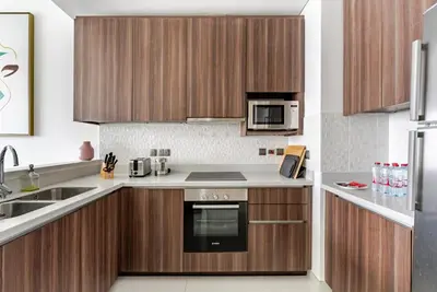 a kitchen with wooden cabinets and a microwave at Prestige Avani Residence 2BR with Golf Course View in Dubai