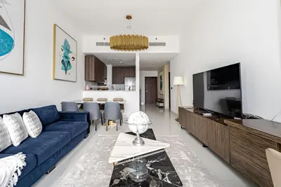 a living room with a blue couch and a tv at Prestige Avani Residence 2BR with Golf Course View in Dubai