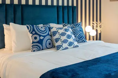 a bed with blue and white pillows on it at Brand New Luxury Family Friendly 3 beds Near Burj AlArab Ultimate Stay in Dubai