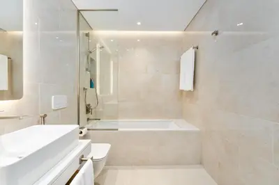a white bathroom with a tub and a sink at Brand New Luxury Family Friendly 3 beds Near Burj AlArab Ultimate Stay in Dubai