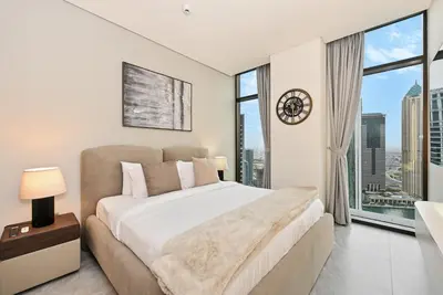 a bedroom with a large bed and a large window at Curated High Floor 1BR-Sofa Bed Water View Peninsula 1 in Dubai