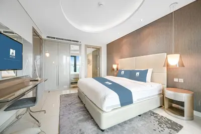 a bedroom with a bed and a desk and a television at Amazing 1BR DAMAC Towers by Paramount in Dubai