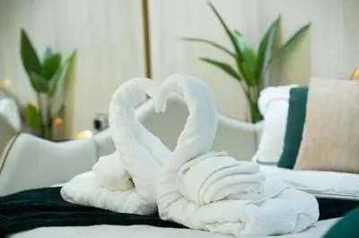 two towels shaped like swans sitting on a bed at Binghatti Aurora, JVC Dubai - Unique Round Bed Experience with pool view in Dubai