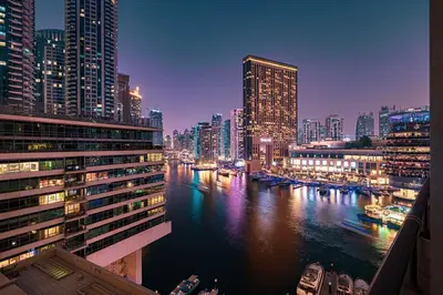 a city skyline at night with a river and buildings at Luxury Duplex Penthouse with Stunning Marina Views in Dubai