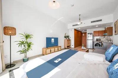 a living room with a large bed and a kitchen at Amazing View Studio Lago Vista IMPZ in Dubai