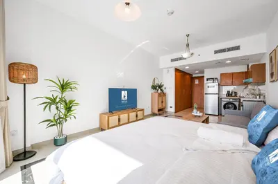 a bedroom with a large white bed and a kitchen at Amazing View Studio Lago Vista IMPZ in Dubai